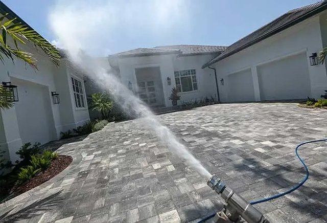 Exterior building washing on a paver driveway and white home