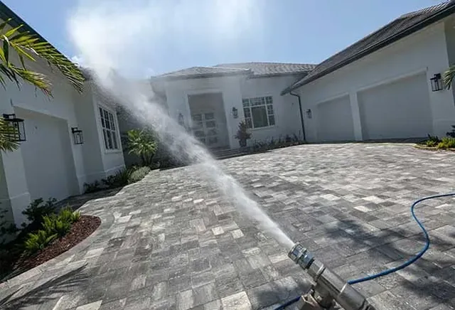 Exterior building washing on a paver driveway and white home